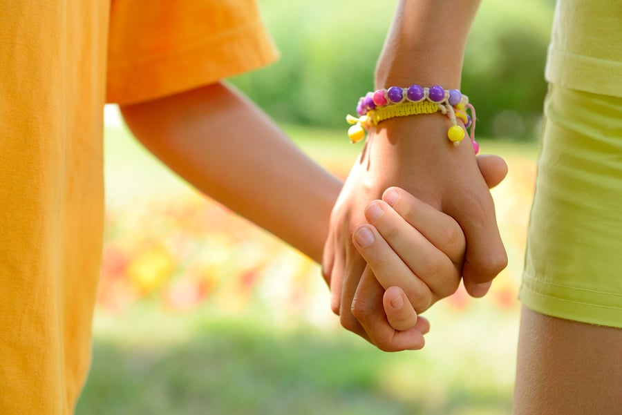 Friendship Bracelets - hands of children over summer nature outdoor